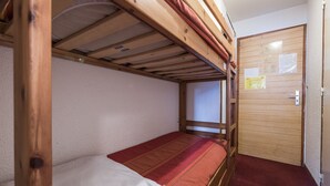 A bunk bed room with a wooden door and a bulletin board.