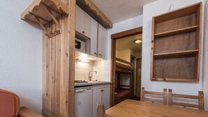 A compact kitchen with wooden cabinets, a sink, and a dining table with chairs.