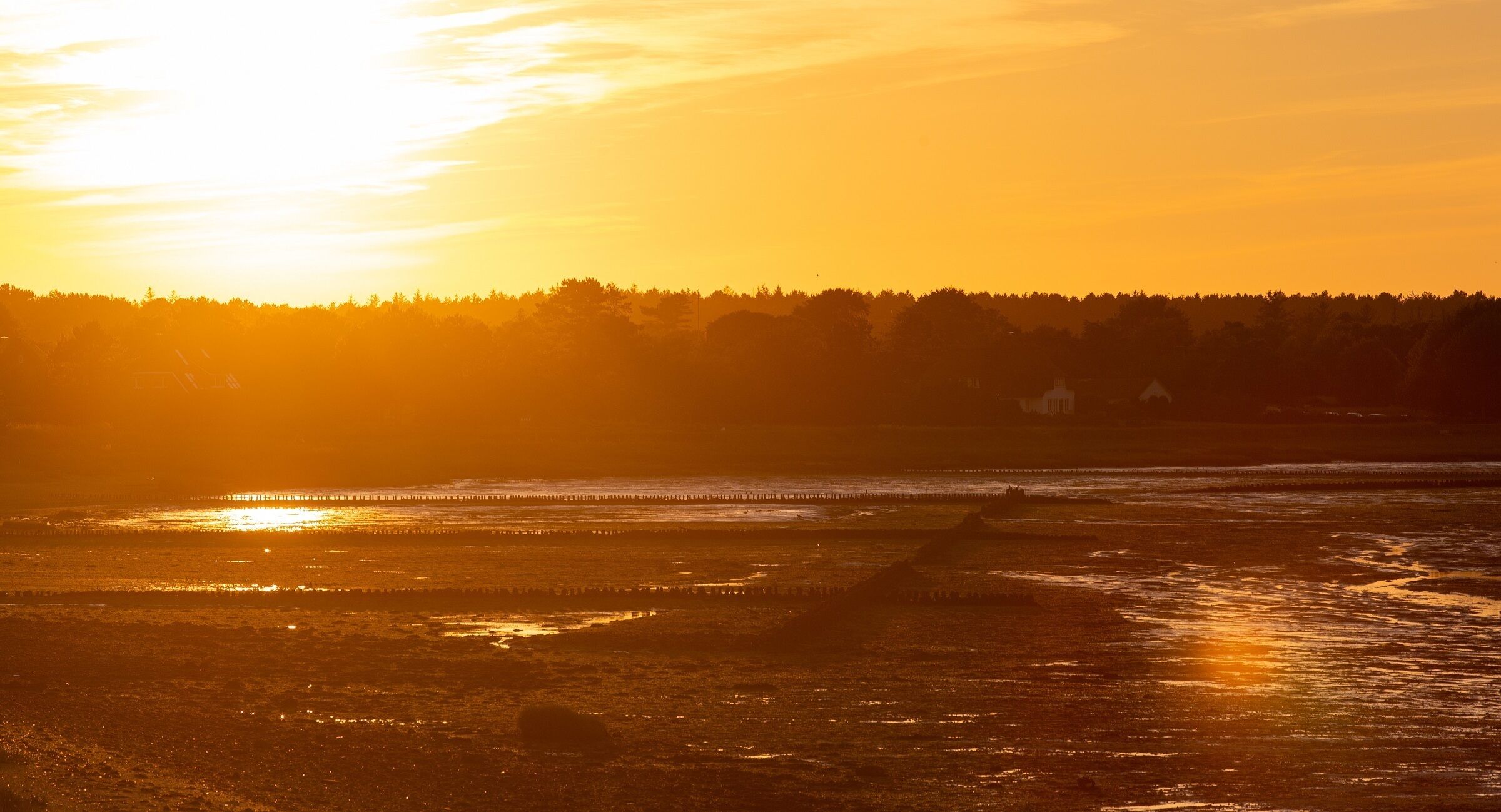 A sunset over a beach with a pier extending into the water.