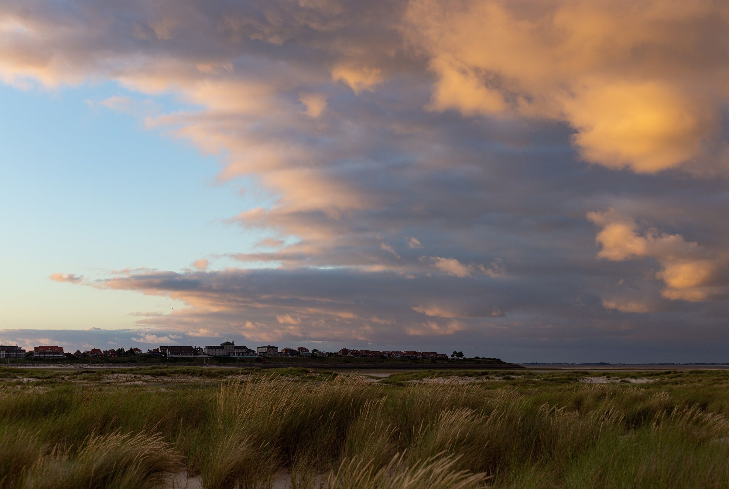 A coastal landscape with a flat terrain and a distant town.
