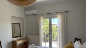 Un dormitori amb un llit gran, un taulell de fusta, un mirall i una finestra amb cortines.