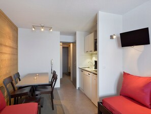 A compact living space with a dining area, kitchenette, and a TV mounted on the wall. - Renovated ski-in/ski-out studio with balcony and pets allowed (Belle Plagne)