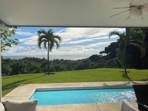 Un espace piscine offrant une vue dégagée sur l’océan et une végétation luxuriante.