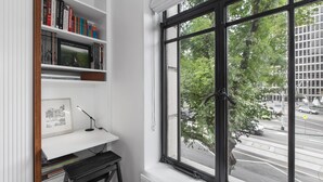 Une pièce avec une grande fenêtre, une bibliothèque et un bureau avec une lampe.