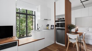 Une cuisine moderne avec des meubles blancs, un four encastré et un coin repas comprenant une table et des chaises.