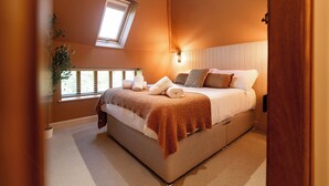 A bedroom with a bed, a window, a plant, and a wooden door. - Dovecote (Dover)