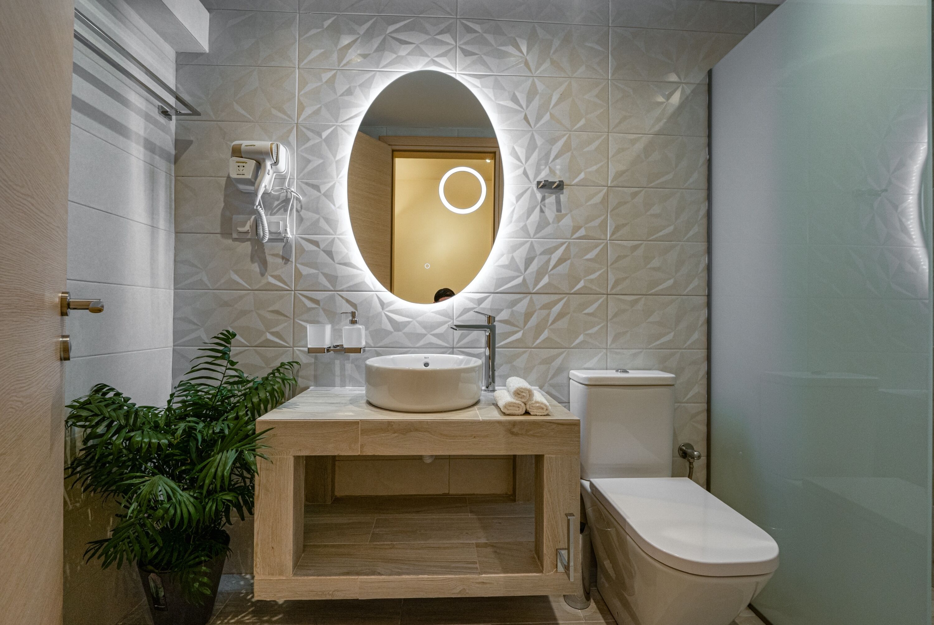Ein modernes Badezimmer mit Waschtisch aus Holz, einem runden Spiegel und einer Toilette.