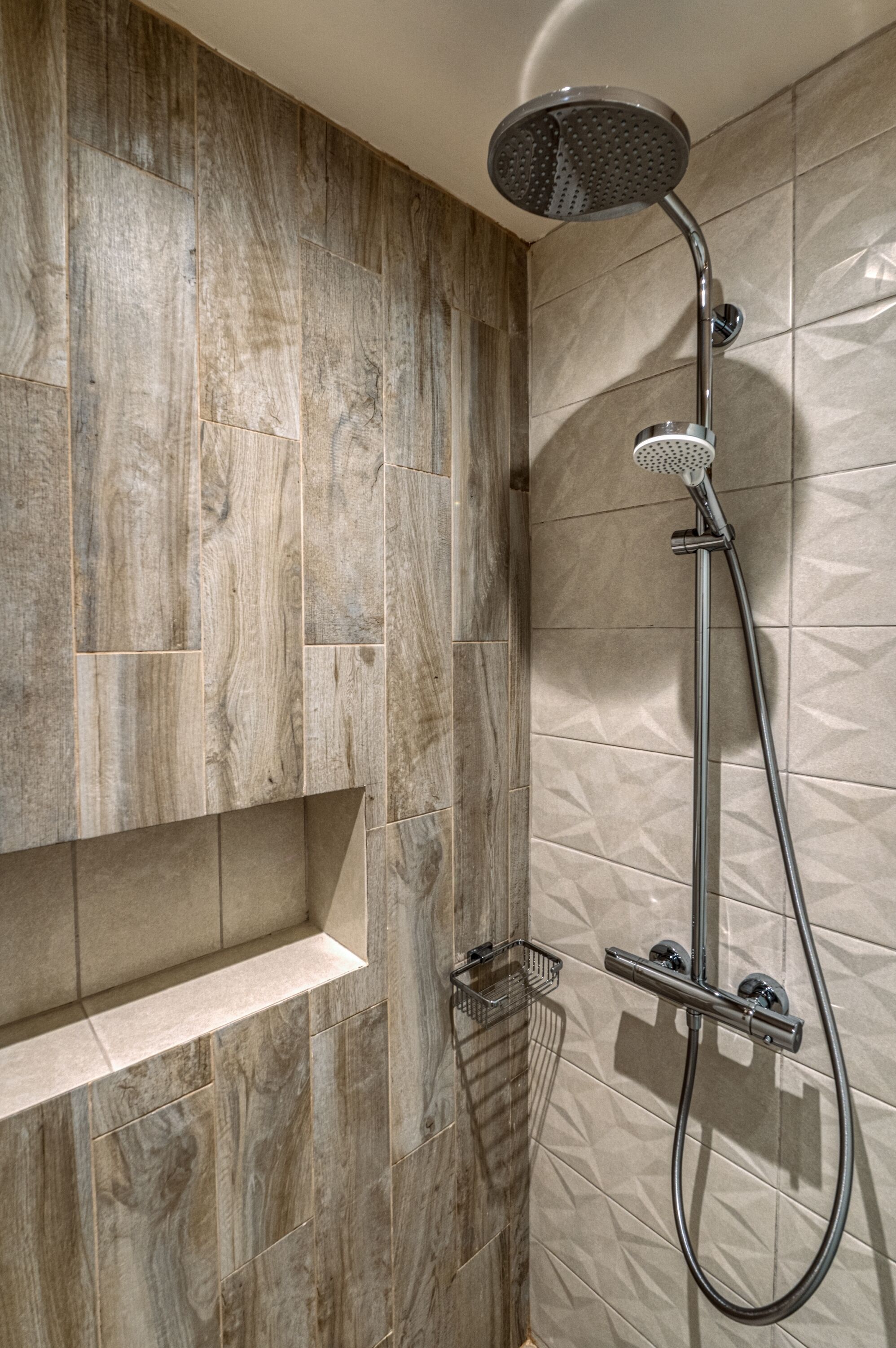 A shower with a rain showerhead and a handheld showerhead, a shelf, and a towel rack.
