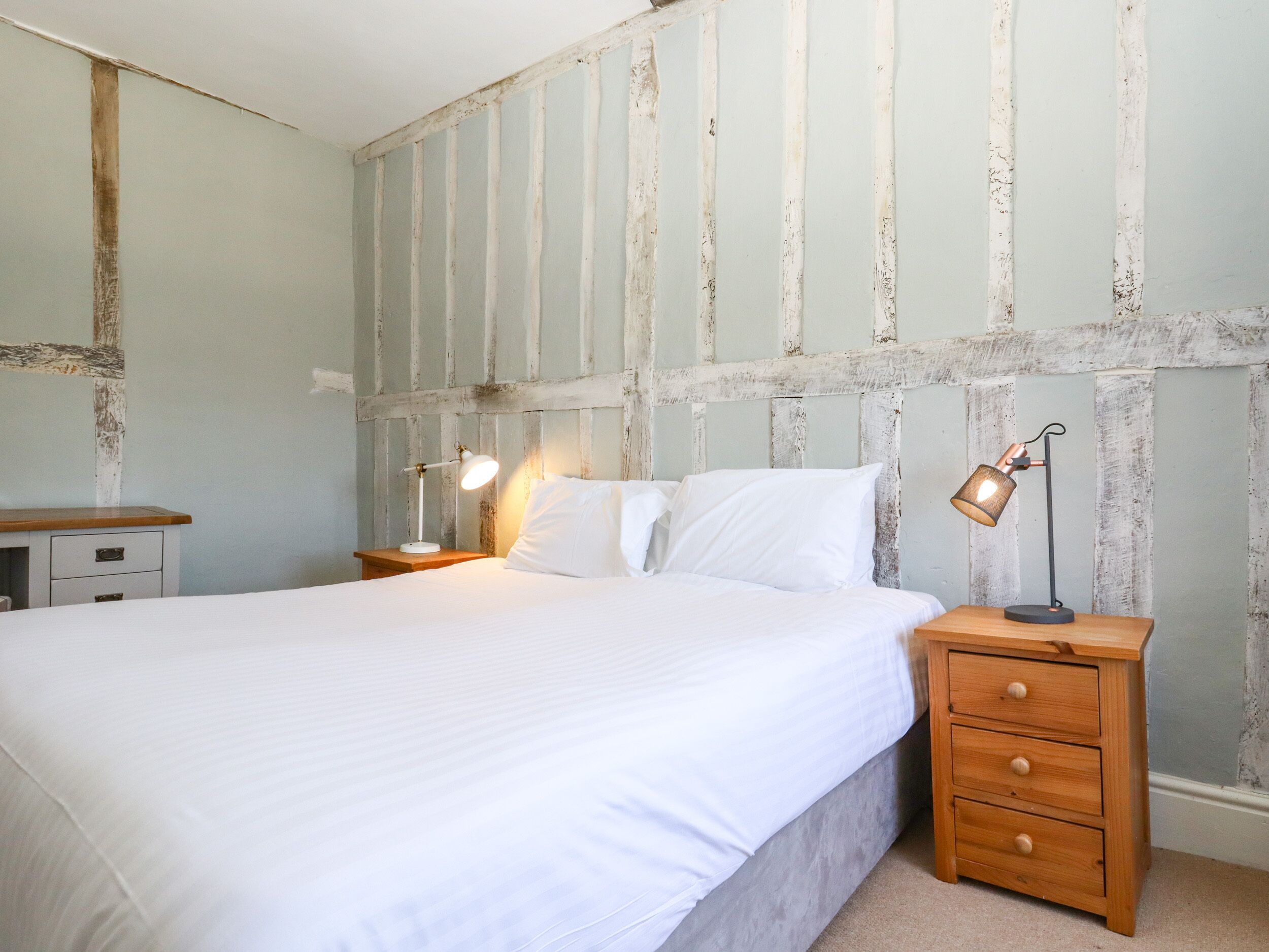 A bedroom with a large bed, two bedside tables, and a wooden nightstand.