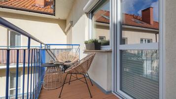 A balcony with wicker furniture, a small table, and a potted plant.