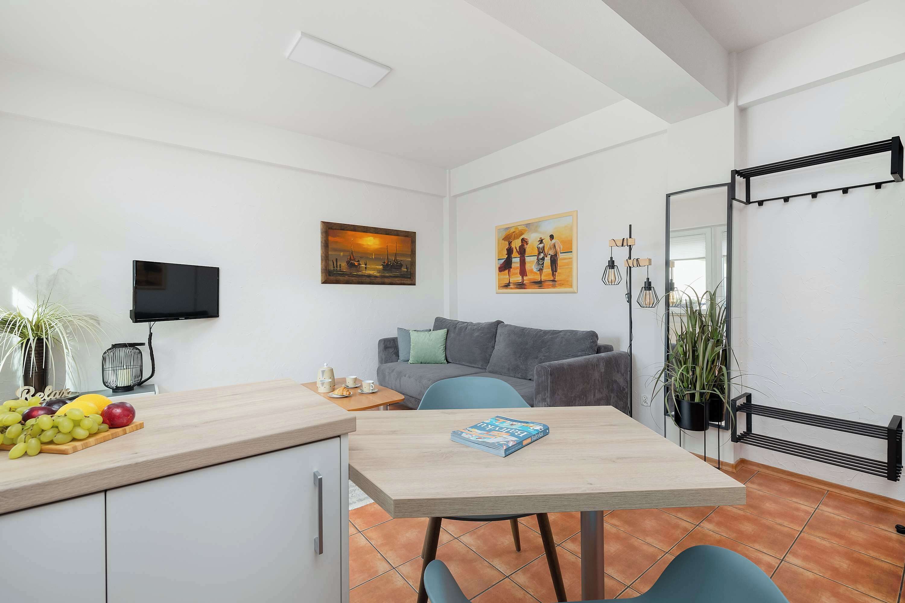 Ein gemütlicher Wohnbereich mit Küchenzeile, Essplatz, einer Couch und einem an der Wand befestigten Fernseher.