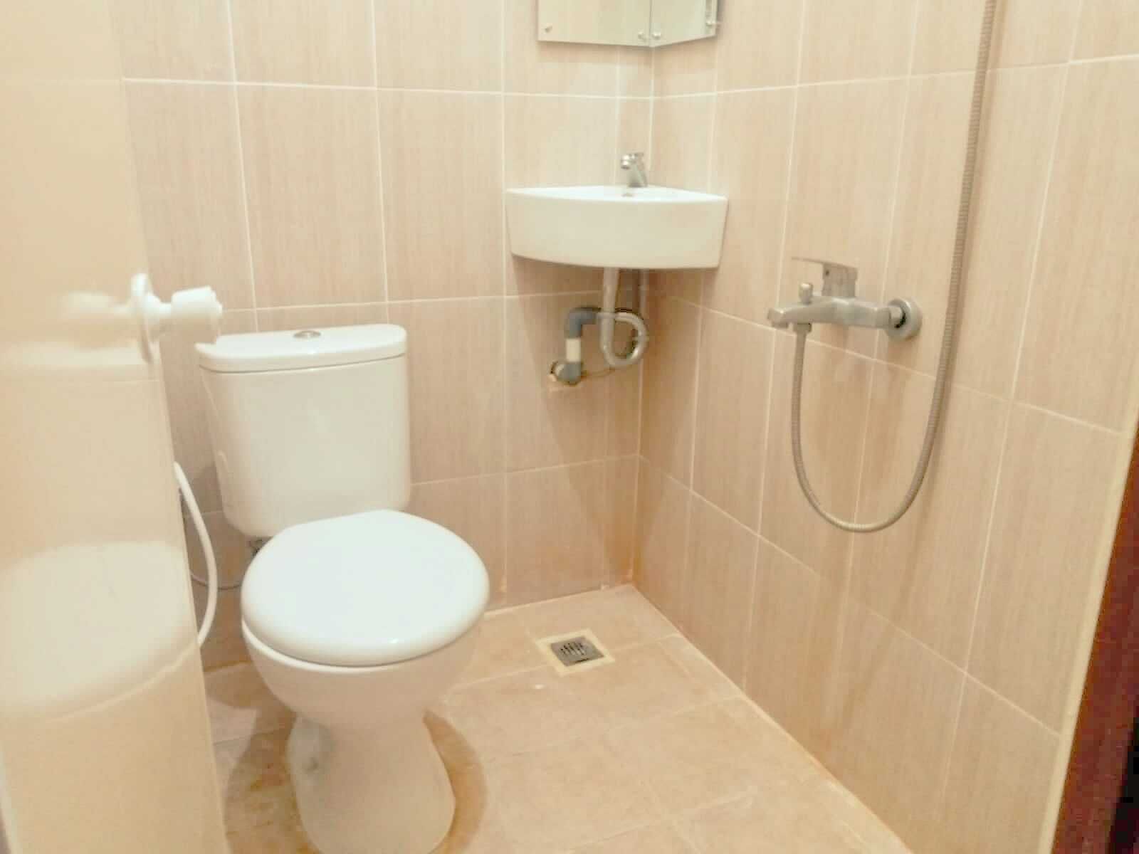 Un baño pequeño y limpio con inodoro, lavamanos y ducha.