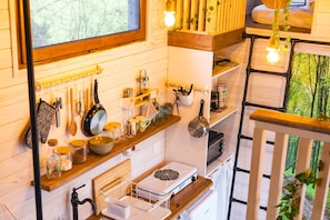 Una cocina con estantes de madera, utensilios colgantes y una estufa.