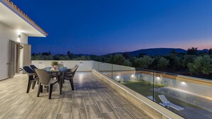 A rooftop terrace with a dining table and chairs, a small garden area, and a view of the surrounding landscape. - Villa Agalliu (Zakynthos)