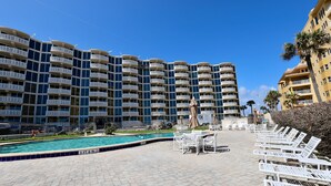Ein Hotel mit mehreren Balkonen, einem Schwimmbad und Sitzgelegenheiten im Freien.