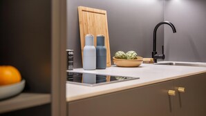 A modern kitchen with a built-in stove, a black faucet, and a wooden cutting board.