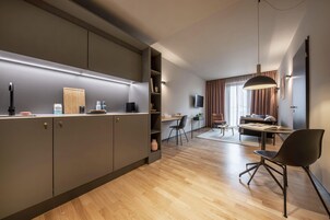 A modern kitchen with built-in appliances, a dining area with a table and chairs, and a living room with a sofa and a TV.