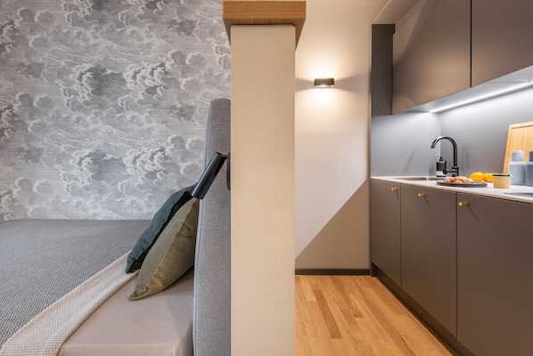 Eine moderne Küche mit grauer Arbeitsplatte, einem schwarzen Wasserhahn und einem Holzkorpus.