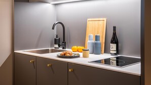A modern kitchen with a built-in stove, a sink, and a wooden cutting board.