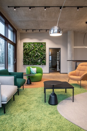 A modern office space with a green sofa, a beige sofa, a black coffee table, and a green carpet.