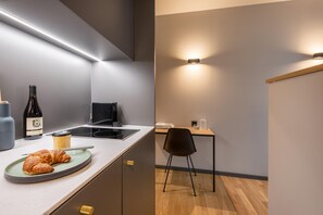 A modern kitchen with a built-in stove, a dining area with a table and chairs, and a bottle of wine on the counter.