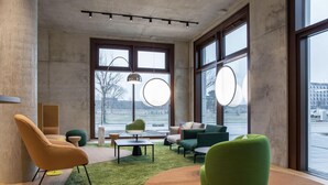 A modern interior with large windows, a green sofa, a wooden coffee table, and a green chair.