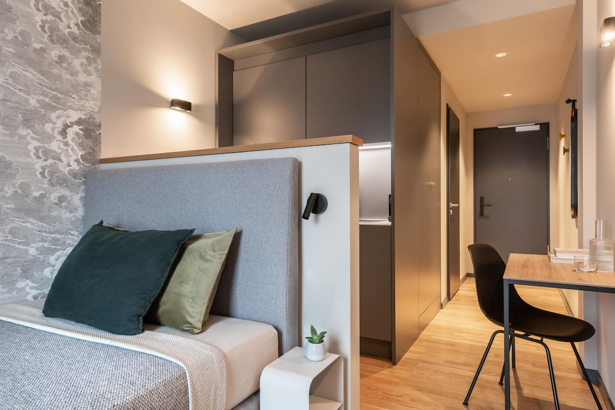 Ein modernes Schlafzimmer mit einem Bett, einem Nachttisch und einer kleinen Pflanze.
