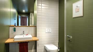 A modern bathroom with a white sink, a toilet, and a shower.