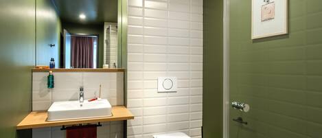 A modern bathroom with a white sink, a toilet, and a shower.