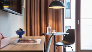 Une pièce moderne avec une table ronde, une chaise, un saladier de fruits, une bouteille d’eau et une lampe.