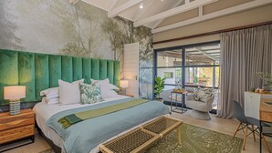 A modern bedroom with a large bed, a green headboard, a bench, and a view of the outdoors through a glass door.