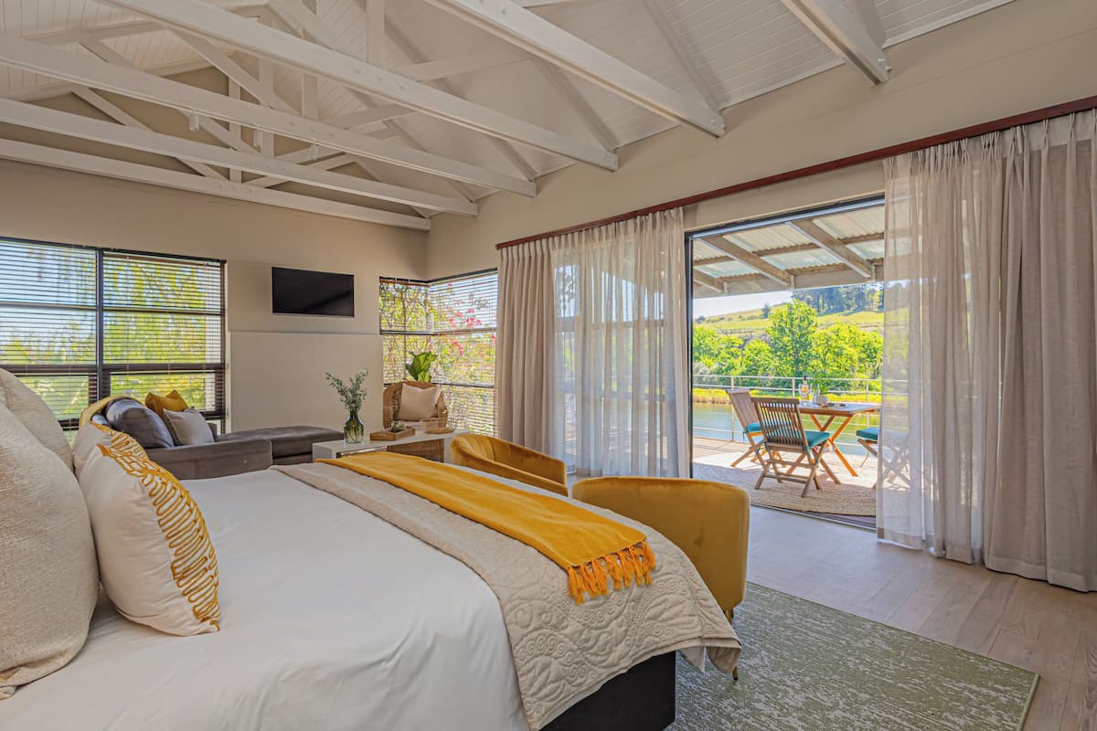 Een slaapkamer met een groot bed, een bank, een eettafel en uitzicht op het landschap.