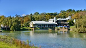 A lakeside property with a large house featuring a covered patio and a boat dock.