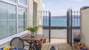 A patio with a table, chairs, a vase of flowers, and potted plants. - 2 The Coach House (Pentraeth)