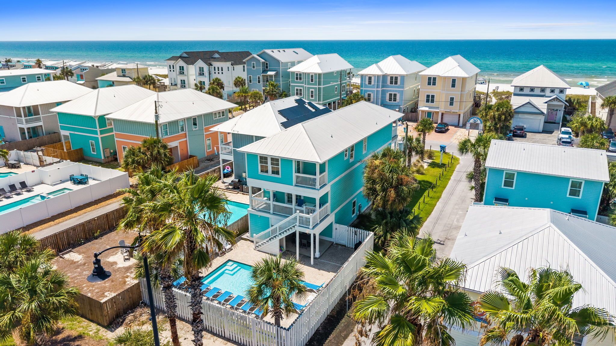 A coastal residential area with multiple two-story houses, a swimming pool, and a clear view of the ocean.