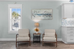 A room with two chairs, a table with a lamp, a painting, and a cabinet. - Just Beachy Private Pool! Just 20 Steps to the beach! Incredible Home (PANAMA CITY BEACH)