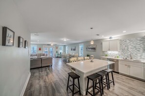 A spacious kitchen with a central island, bar stools, and a dining area with chairs.
