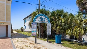 A beach access sign with palm trees and a building in the background. - Just Beachy Private Pool! Just 20 Steps to the beach! Incredible Home (PANAMA CITY BEACH)