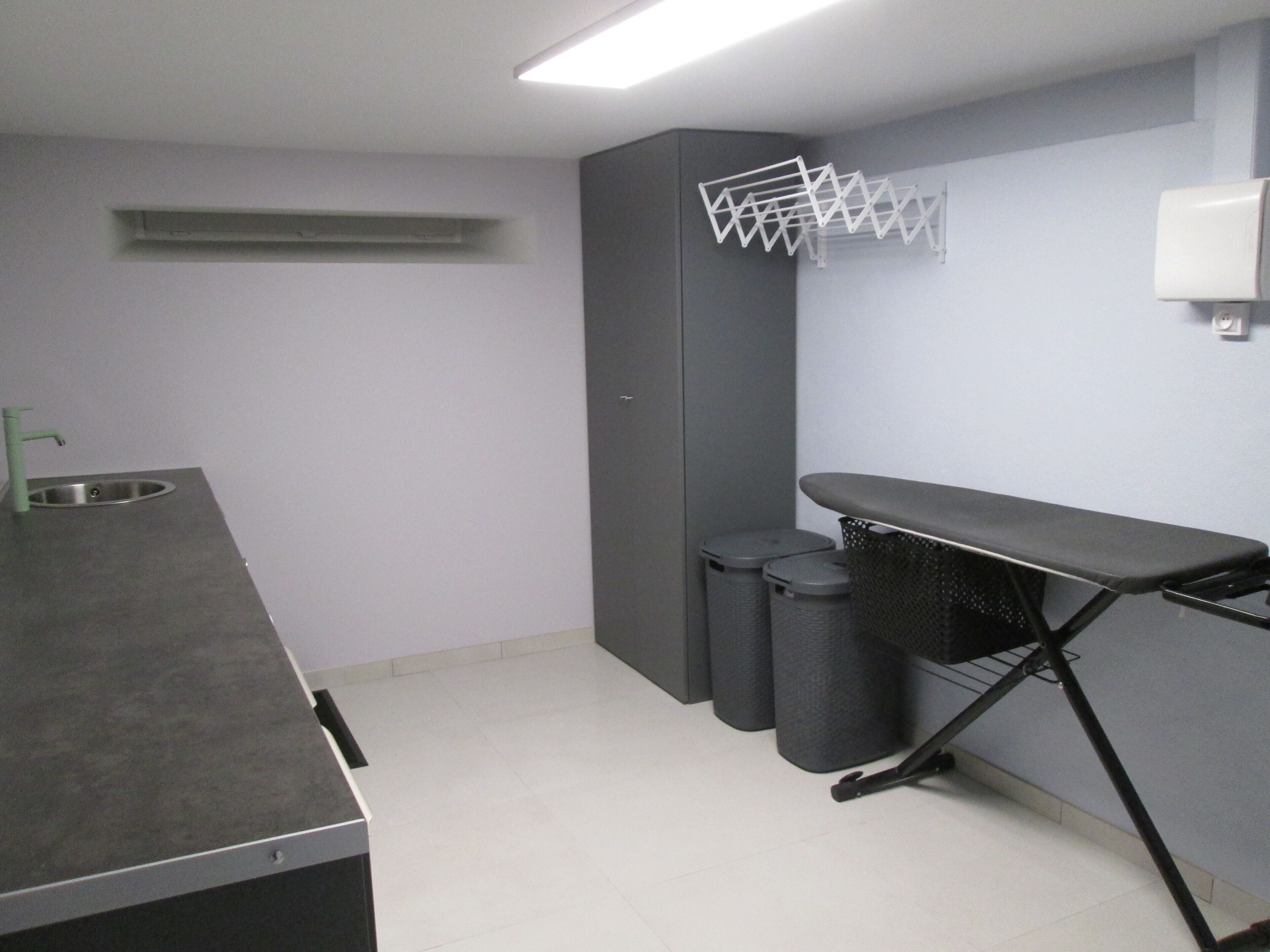 Une petite pièce propre, équipée d’un lavabo, d’un étendoir et de deux poubelles.