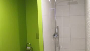 A modern bathroom with a shower, toilet, and green walls.