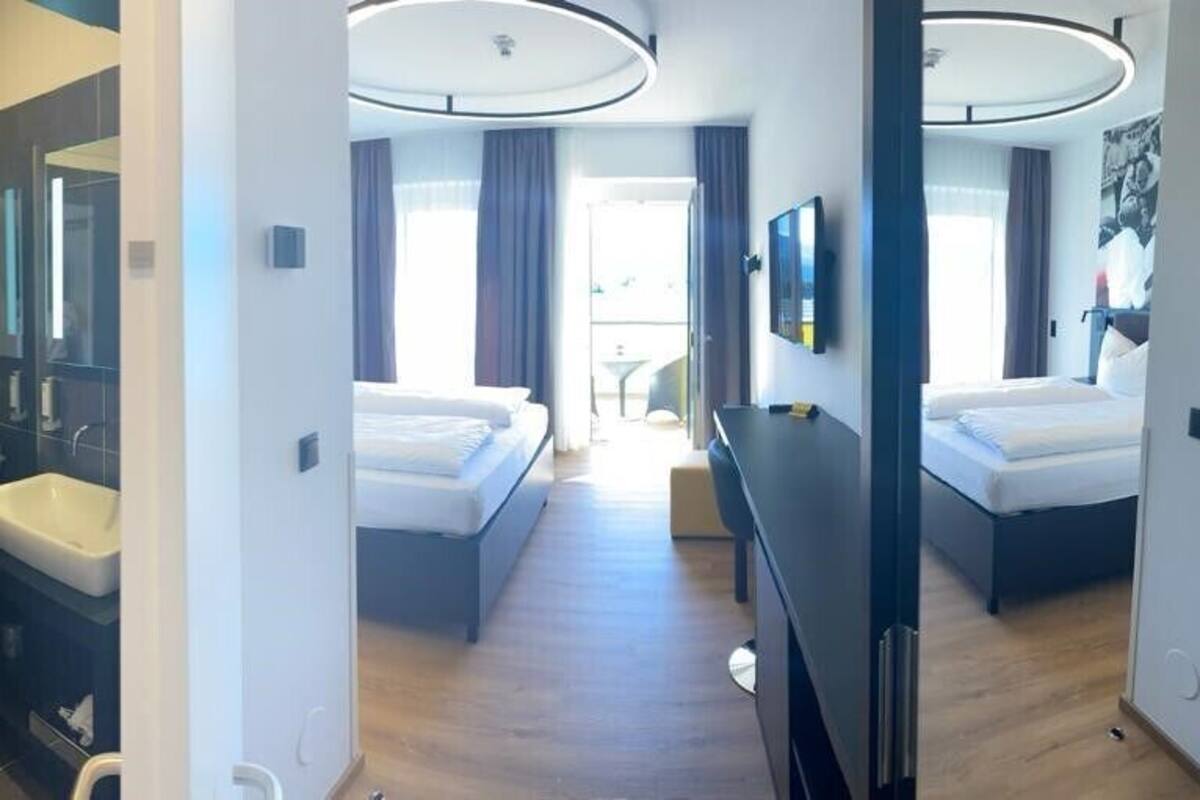A modern hotel room with a separate bathroom, a bed, a desk, and a view of the outdoors.