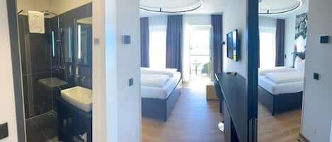 A modern hotel room with a separate bathroom, a bed, a desk, and a view of the outdoors.