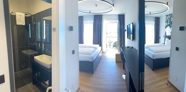 Habitación de hotel moderna con baño privado, cama, escritorio y vistas al exterior.