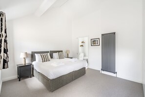 A modern bedroom with a large bed, bedside tables, a radiator, and a framed picture on the wall.