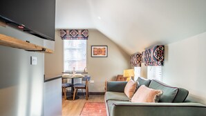 Una sala acogedora con sofá, una mesa de comedor con sillas y una zona de cocina con refrigerador.