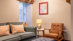 A living room with a sofa, armchair, and ottoman, a lamp, and a framed map on the wall. - The Falcon Apartment 5 (York)