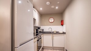 A modern kitchen with white cabinets, a microwave, a toaster, and a sink. - The Falcon Apartment 5 (York)