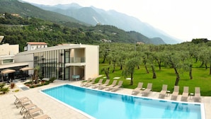 Un hotel moderno con piscina, sillones de descanso y vistas a las montañas.