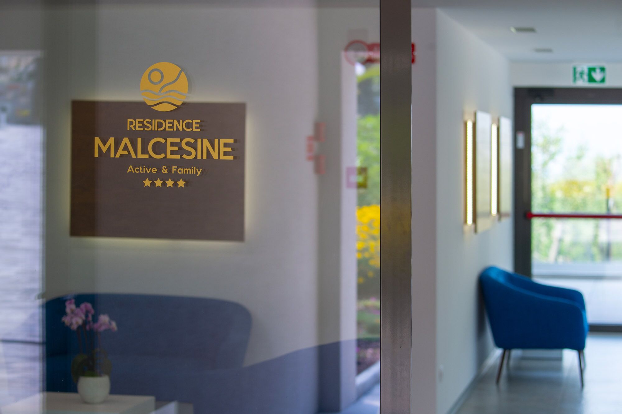 Un espace d’accueil avec une enseigne indiquant « RÉSIDENCE MALCESINE, pour des séjours actifs et en famille » et une note de quatre étoiles.
