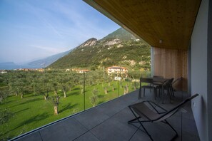Ein Balkon mit Blick auf eine gebirgige Landschaft und ein Gebäude mit rotem Dach.
